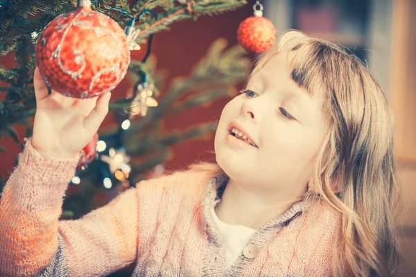 若い女の子は、いくつかのクリスマスのつまらないものを保持しているクリスマス ツリーを飾る — ストック写真