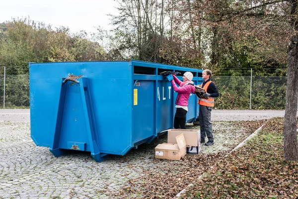 Mujer y hombre poniendo papel usado en contenedor en el centro de reciclaje — Foto de Stock