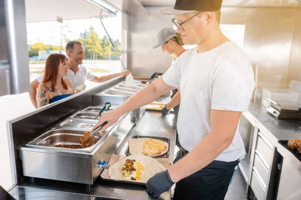 Jovens chefs em um caminhão de alimentos preparando alimentos para seus clientes — Fotografia de Stock
