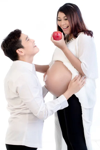 Беременная жена держит яблоко, стоящее рядом с мужем — стоковое фото