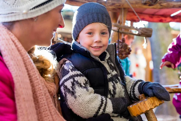 Moeder met zoon en carrousel op kerstmarkt — Stockfoto