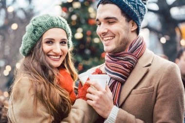 Kadın ve erkek yılbaşı pazarında sıcak şarap içiyor.
