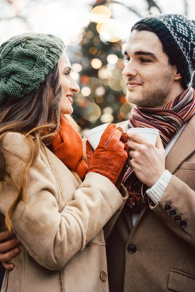 Pareja con copas de vino caliente en el mercado de Navidad — Foto de Stock