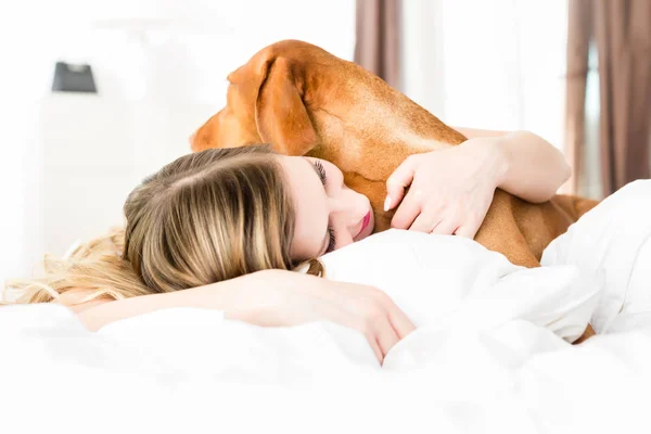 Frau liegt mit Hund im Bett — Stockfoto