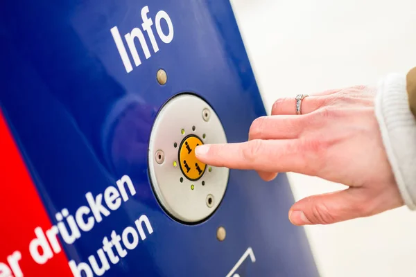 Woman pressing info button of assistance machine in train station — Stock Photo, Image