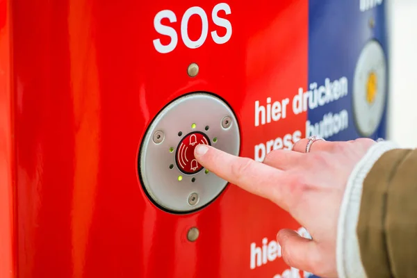 Woman pressing SOS emergency button in train station — Stock Photo, Image