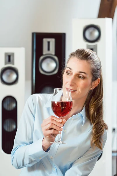 Женщина выпивает бокал вина перед колонками Hi-Fi — стоковое фото