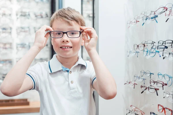 Giovane ragazzo essere molto felice con i suoi nuovi occhiali nel negozio — Foto Stock