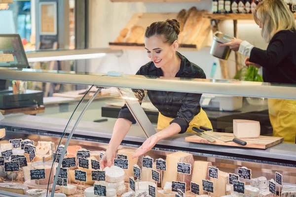 Shop írnok nő a szupermarket kijelző sajt válogatás — Stock Fotó