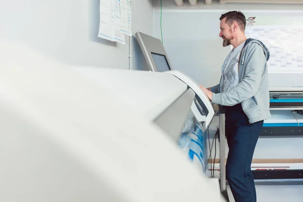 Man aan het werk op groot formaat printer in reclamebureau — Stockfoto