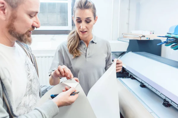 Man and woman discussing a large format print