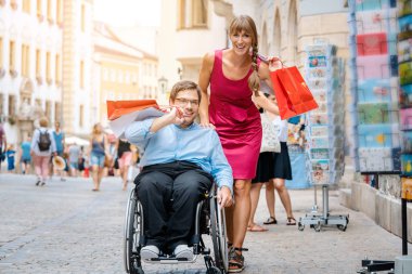 Kadın ve erkekte tekerlekli sandalye ile alışveriş torbaları