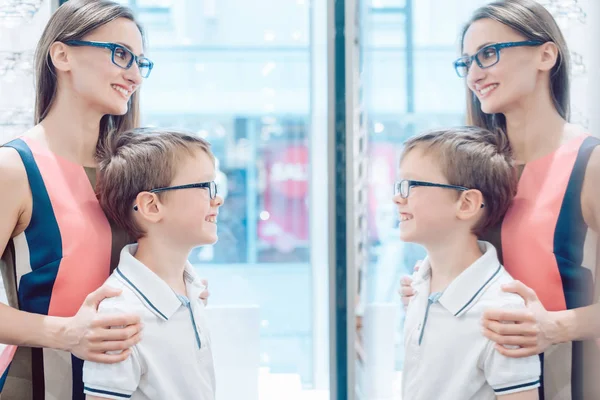 Madre y su hijo probando nuevas gafas en el espejo — Foto de Stock