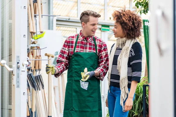 Lavoratore bello aiutare un cliente con la scelta di uno strumento di giardinaggio — Foto Stock