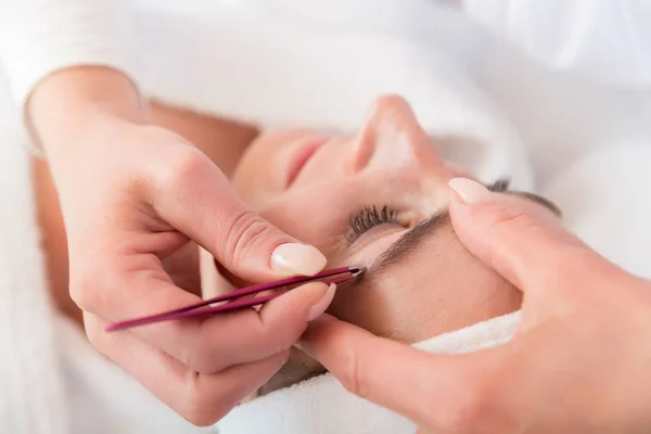 Esthéticienne arrachant les sourcils avec une pince à épiler d'une femme — Photo