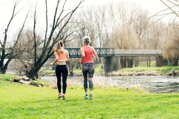 Mujer mayor con hija corriendo por el río — Foto de Stock