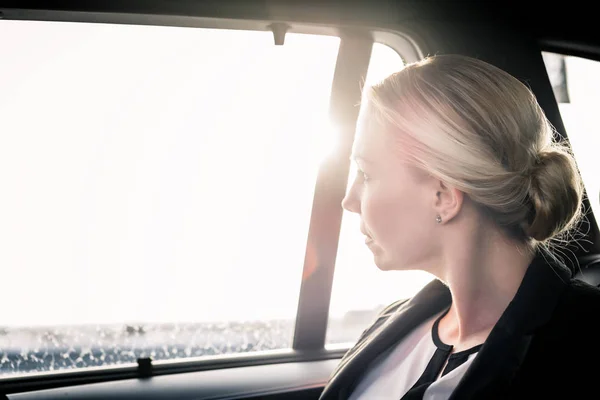 Mujer de negocios mirando a través de la ventana de cristal de un coche —  Fotos de Stock