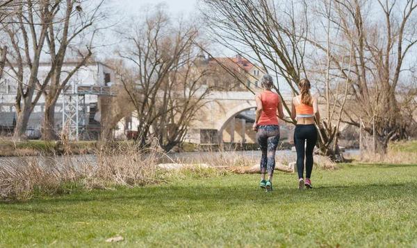 Mother and adult daughter running for sport along the river — Stock Photo, Image