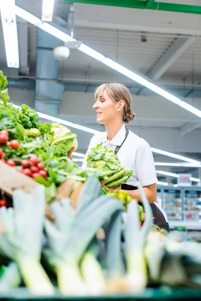 Woman working in a supermarket sorting fruit and vegetables — Stock Photo, Image