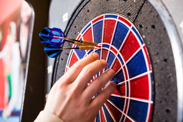 Persons hand removing arrows from dartboard — Stock Photo, Image