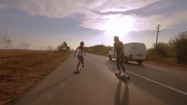 Dvě mladé ženy oblečené v pohodě oblečení závodí s longboardy — Stock video