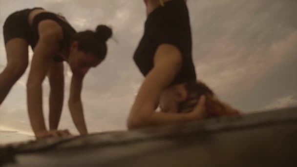 İki kadın bir aracın çatıda başı ve amut pozisyonlar pratik — Stok video
