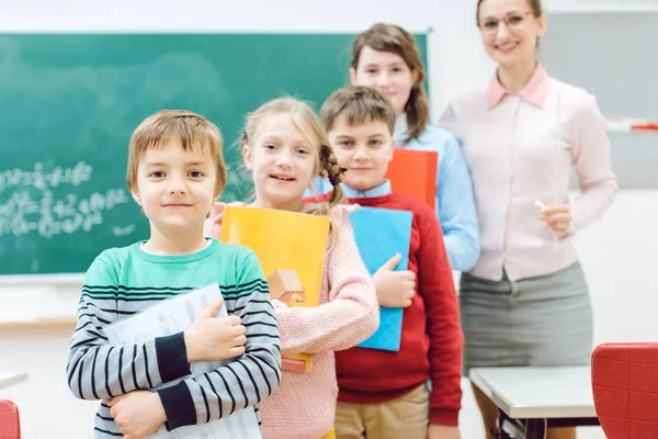 Estudiantes con libros y profesores de pie en clase escolar — Foto de Stock