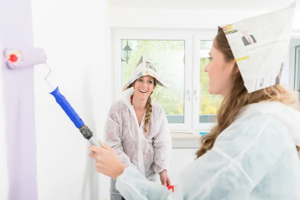 Woman looking at her friend painting the wall — Stock Photo, Image