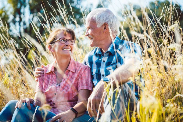 Couple de femme âgée et l'homme assis dans une prairie dans l'herbe — Photo