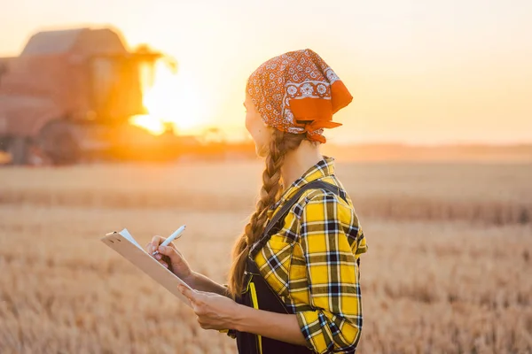 Çiftçi kadın ve hasat makinesini buğday tarlasında birleştirin. — Stok fotoğraf
