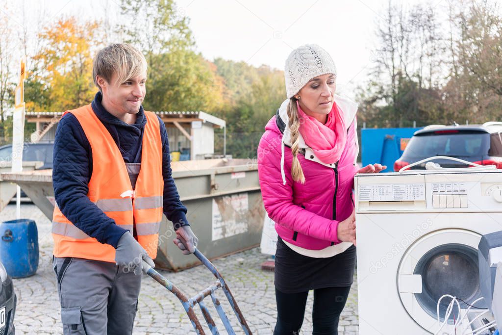 Woman and man giving electrical appliances to recycling center