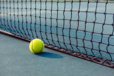 Bir tenis kortu net önünde bir floresan sarı top yakın çekim