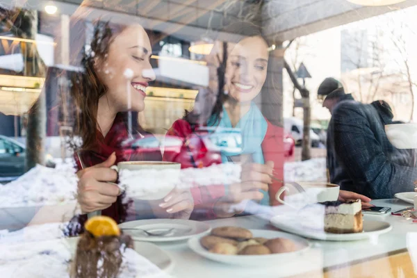 Dua wanita muda dan cantik menikmati kue dan kopi di kafe trendi — Stok Foto