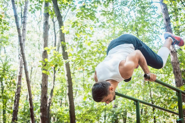 Hombre en el gimnasio al aire libre haciendo ejercicio en las barras paralelas — Foto de Stock