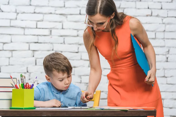 Estudiante haciendo trabajo en la escuela supervisado por su profesor — Foto de Stock