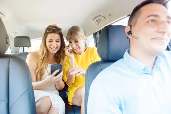 Freundinnen benutzen ihr Handy auf dem Rücksitz des Taxis — Stockfoto