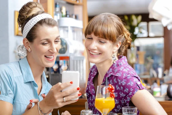 Две женщины смотрят на мобильный телефон — стоковое фото