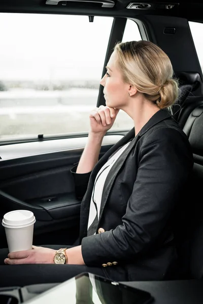 Размышлённая деловая женщина, держащая чашку кофе в машине — стоковое фото