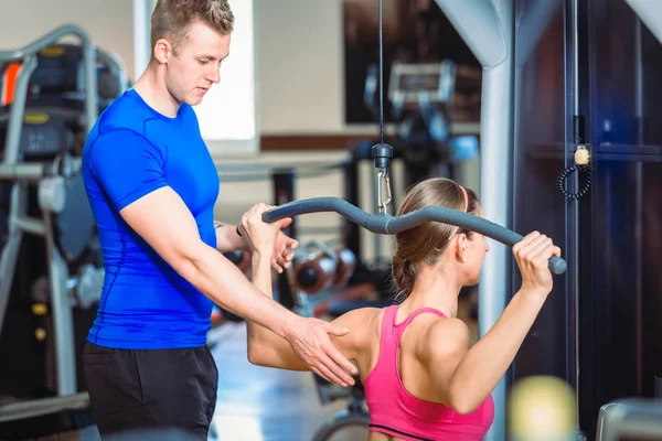 Knappe persoonlijke trainer begeleiden een mooie vrouw in een moderne fitnessclub — Stockfoto