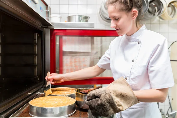 Gebak-Bakker taarten of cakes aanbrengend met oven — Stockfoto