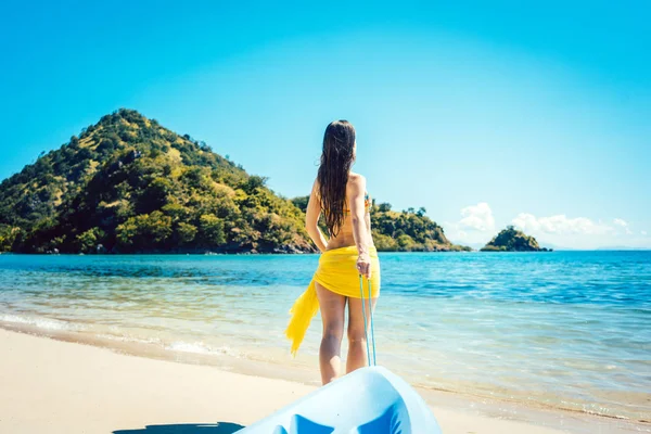 Жінка тягне свій човен до води на пляжі — стокове фото