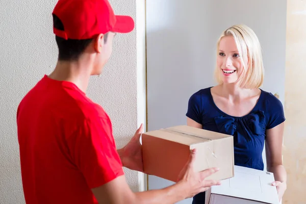 Junge Frau erhält die Kartons vom Zusteller — Stockfoto