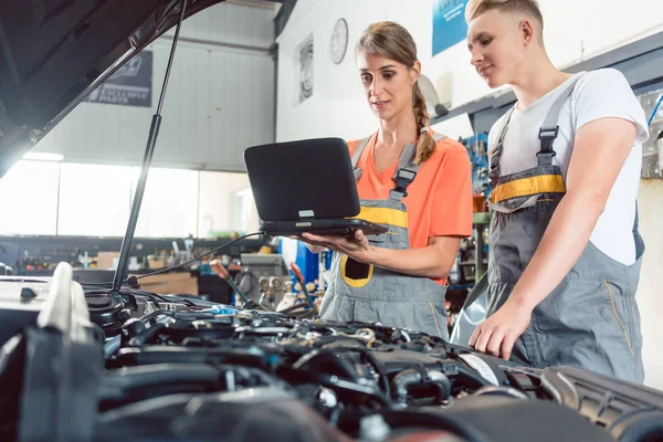 Mecânico automático feminino verificando os códigos de erro do motor — Fotografia de Stock