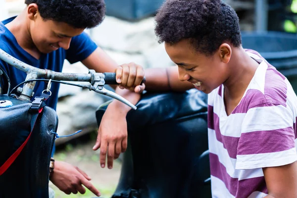 Smiling boys looking at an old bike — Stock Photo, Image