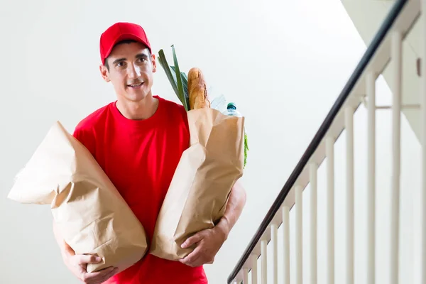 Entrega homem carregando dois sacos de papel de supermercado — Fotografia de Stock
