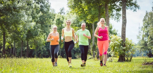 Family with personal Fitness Trainer jogging — Stock Photo, Image