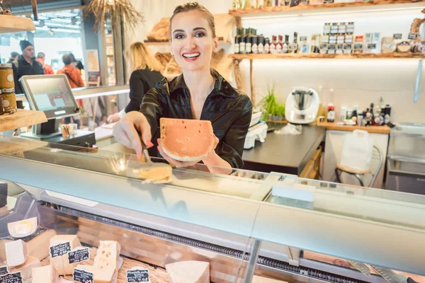 Beautiful woman offering cheese on delicatessen counter — Stock Photo, Image