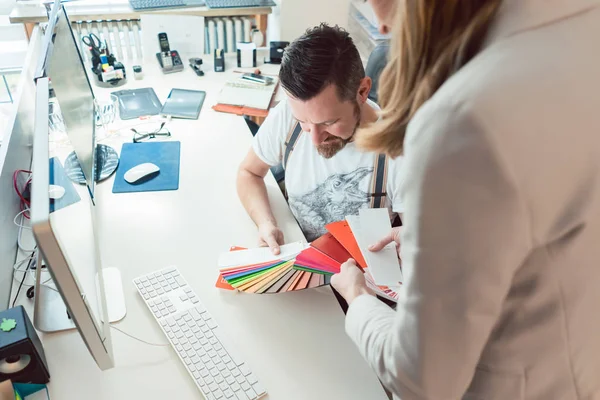 Creativos trabajando en equipo revisando colores para proyecto publicitario — Foto de Stock