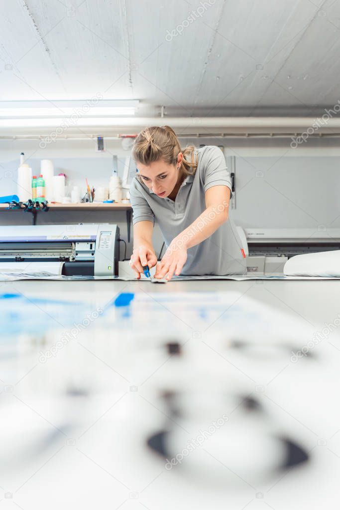 Woman cutting signs or vinyl wraps producing advertising materials