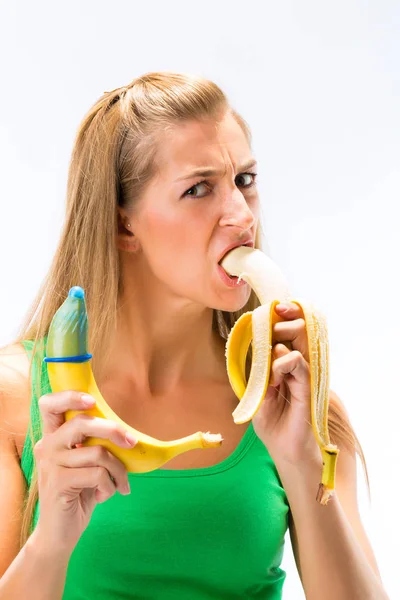 Nő étkezési banán, és bemutatja a más banán, miután óvszer — Stock Fotó